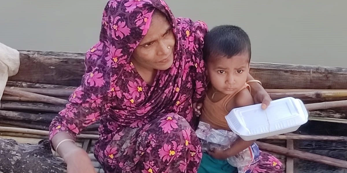 Une femme sur un radeau avec son enfant. Elle vient de recevoir un colis alimentaire. csi